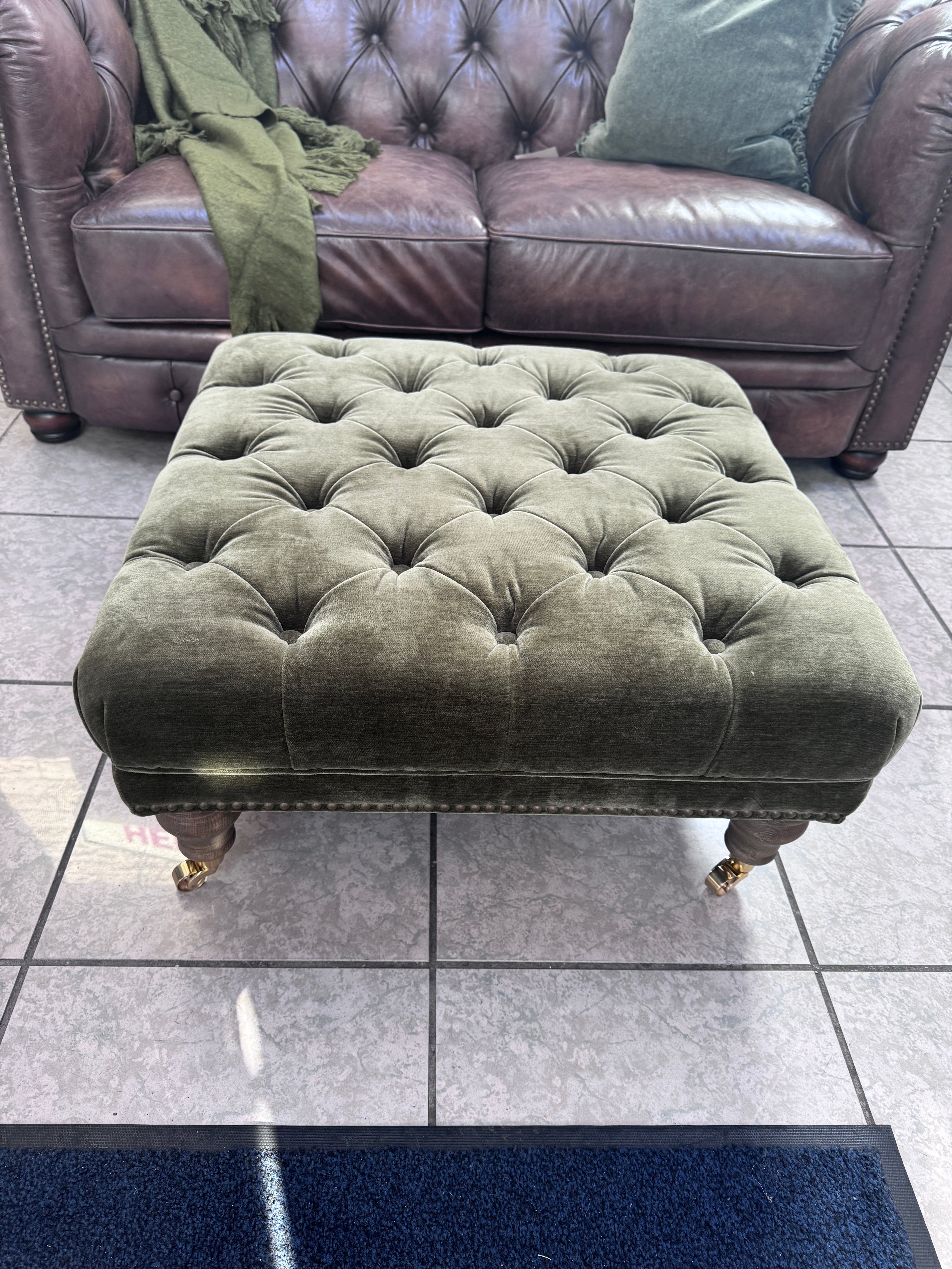 Shackleton square button top footstool with castors in Pine green velvet